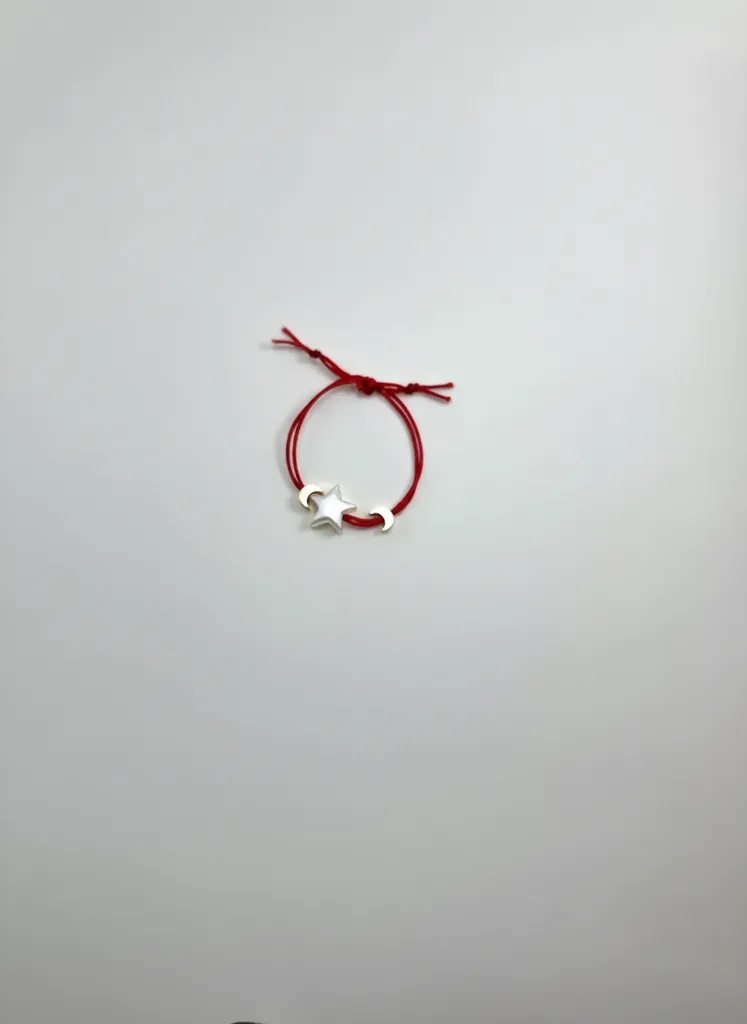 Stylish bracelet with a gold-colored crescent and star figure on a red cord.